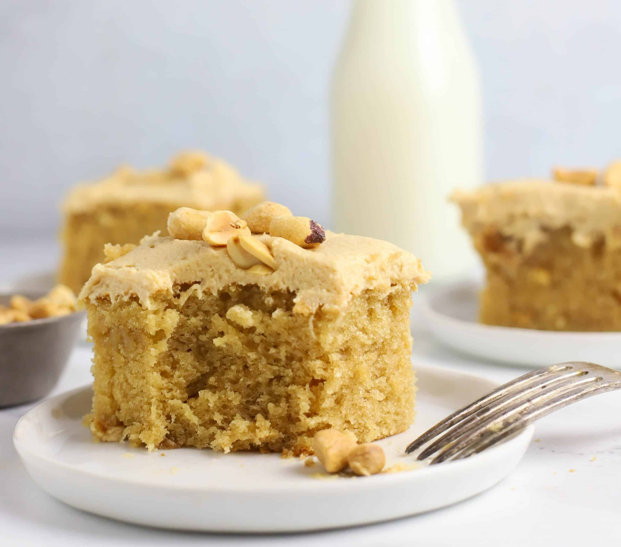 slice of peanut butter cake on a plate topped with peanut butter cream cheese frosting