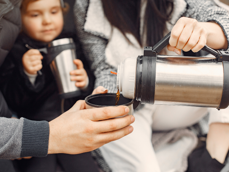 Família toma café de uma garrafa térmica. Foto: Helgy - Canva