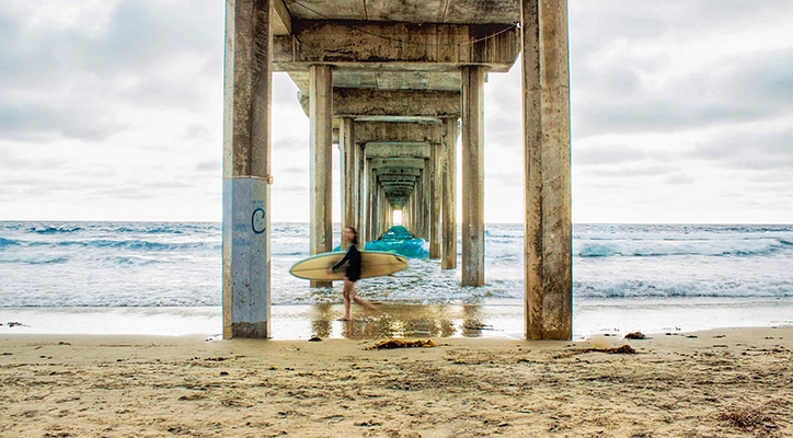 A surfer under a boardwalk.