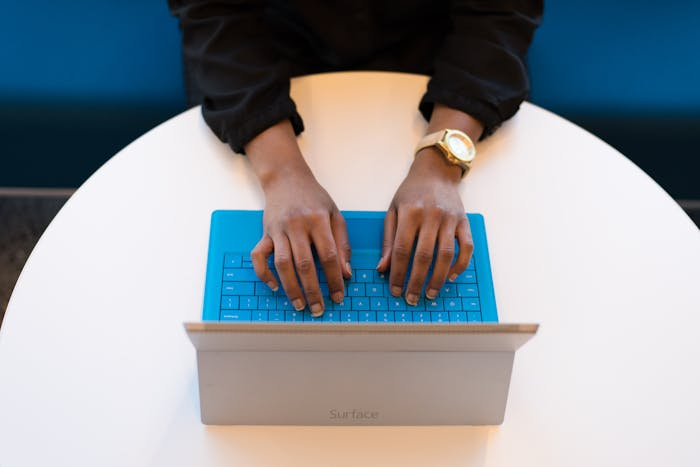 Woman typing on blue laptop