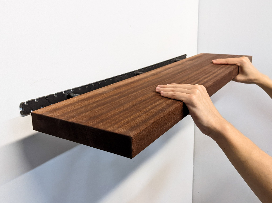 A thick mahogany floating wall shelf in the process of being installed 