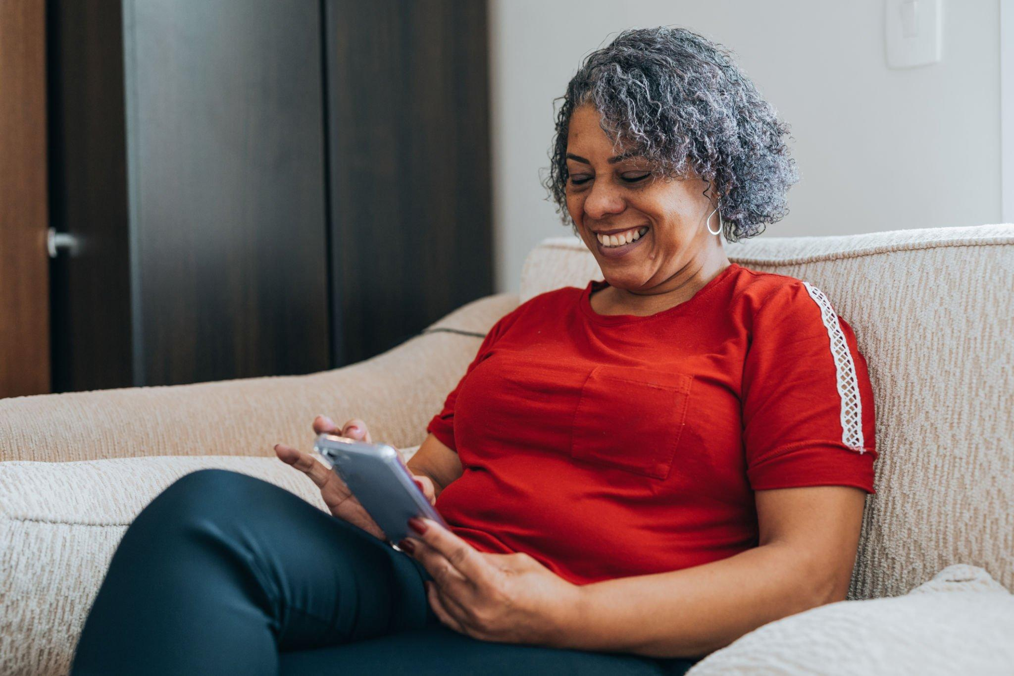 A person smiling while looking at their phone screen to monitor and prevent severe hypoglycemia.