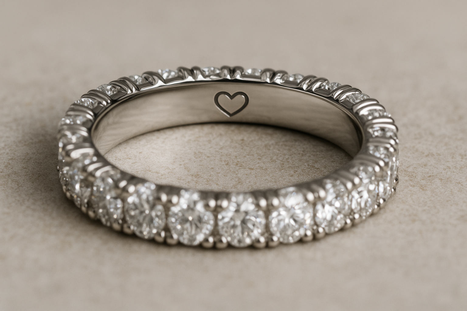 Prabangi deimantinė juostelė su briliantais ratu ir subtilia širdelės graviruote žiedo viduje. Jei pageidaujate kitokio apšvietimo ar metalo atspalvio, praneškite