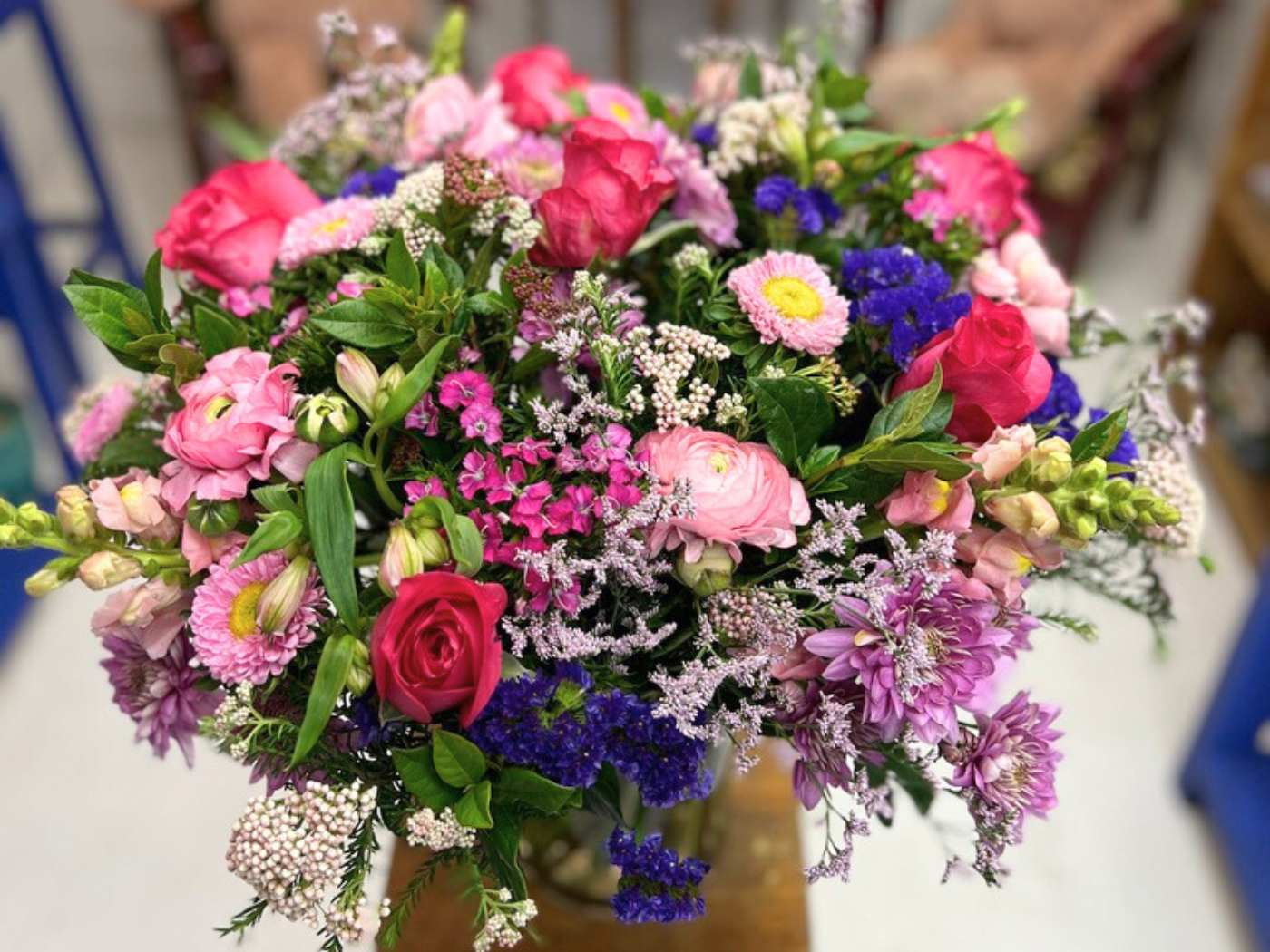 A vibrant bouquet overflowing with an assortment of flowers including pink roses, magenta asters, and delicate lilac blooms, elegantly arranged and featured as part of the Flowers By Occasion Collection at Fabulous Flowers and Gifts.