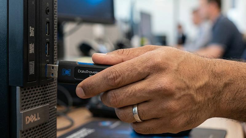 A technician inserting a USB flash drive into a USB port