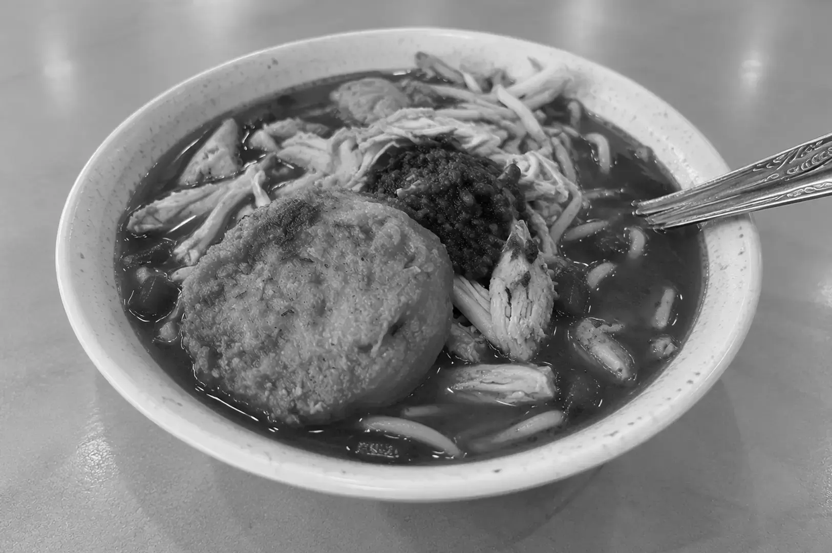 Mee rebus served in a bowl, with yellow noodles covered in rich gravy and finished with traditional garnishes.