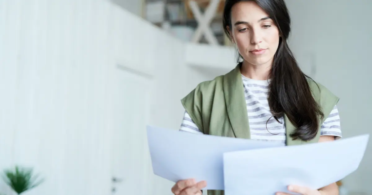 Woman holding completed financial documents, highlighting the difference between balance sheet and income statement.