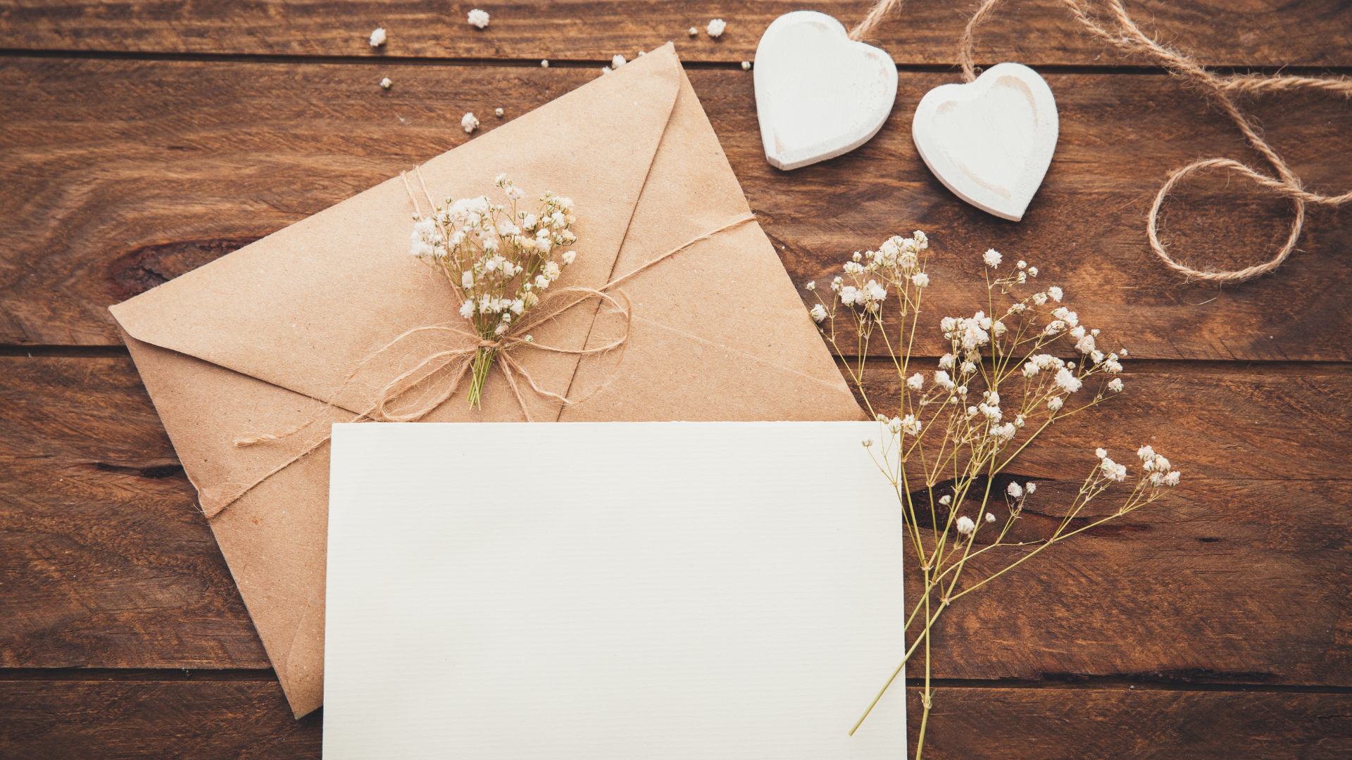 envelope with card, string and flowers on a wooden table