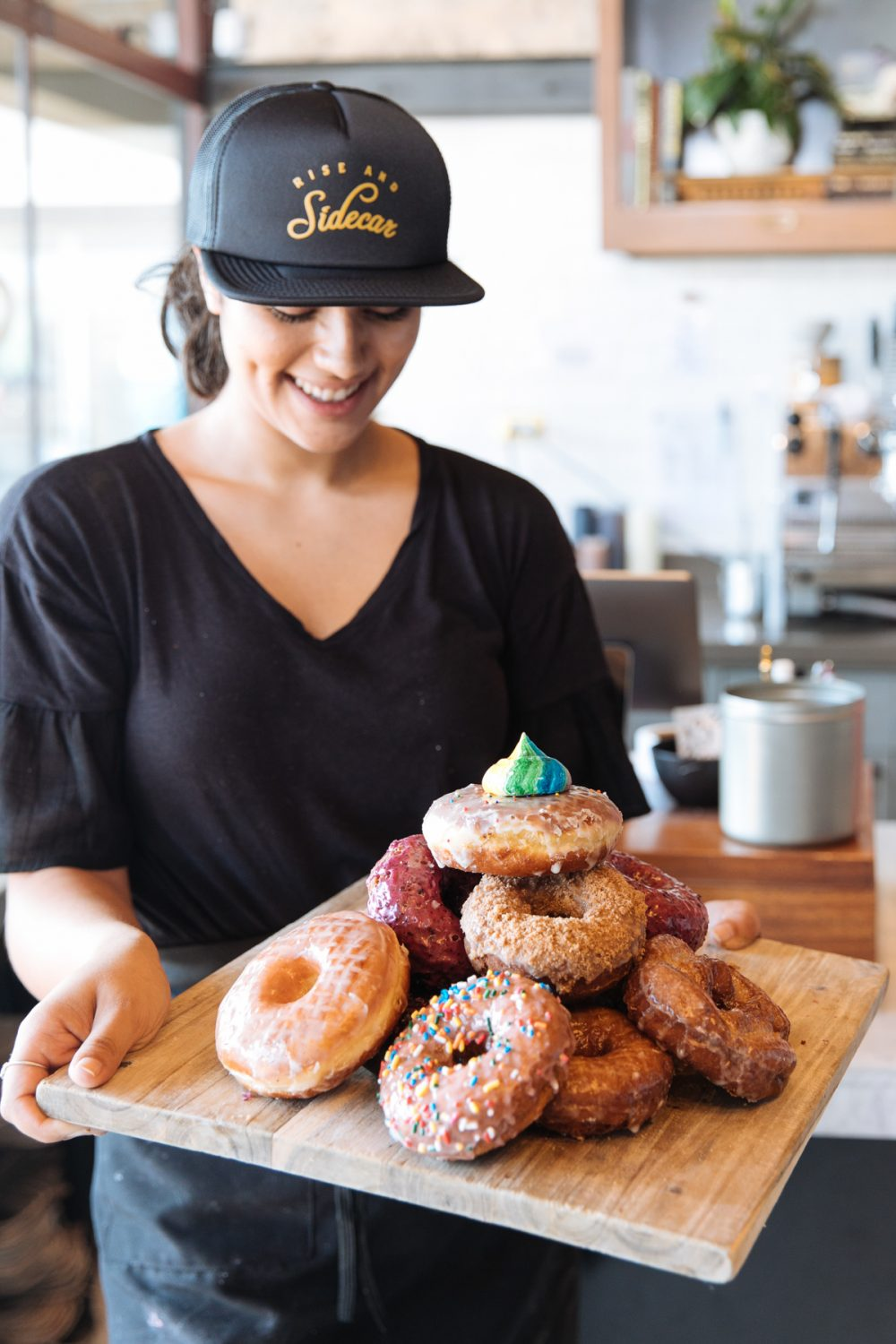 Woman with hat holding a plate of donuts at Sidecar Doughnuts in Santa Monica