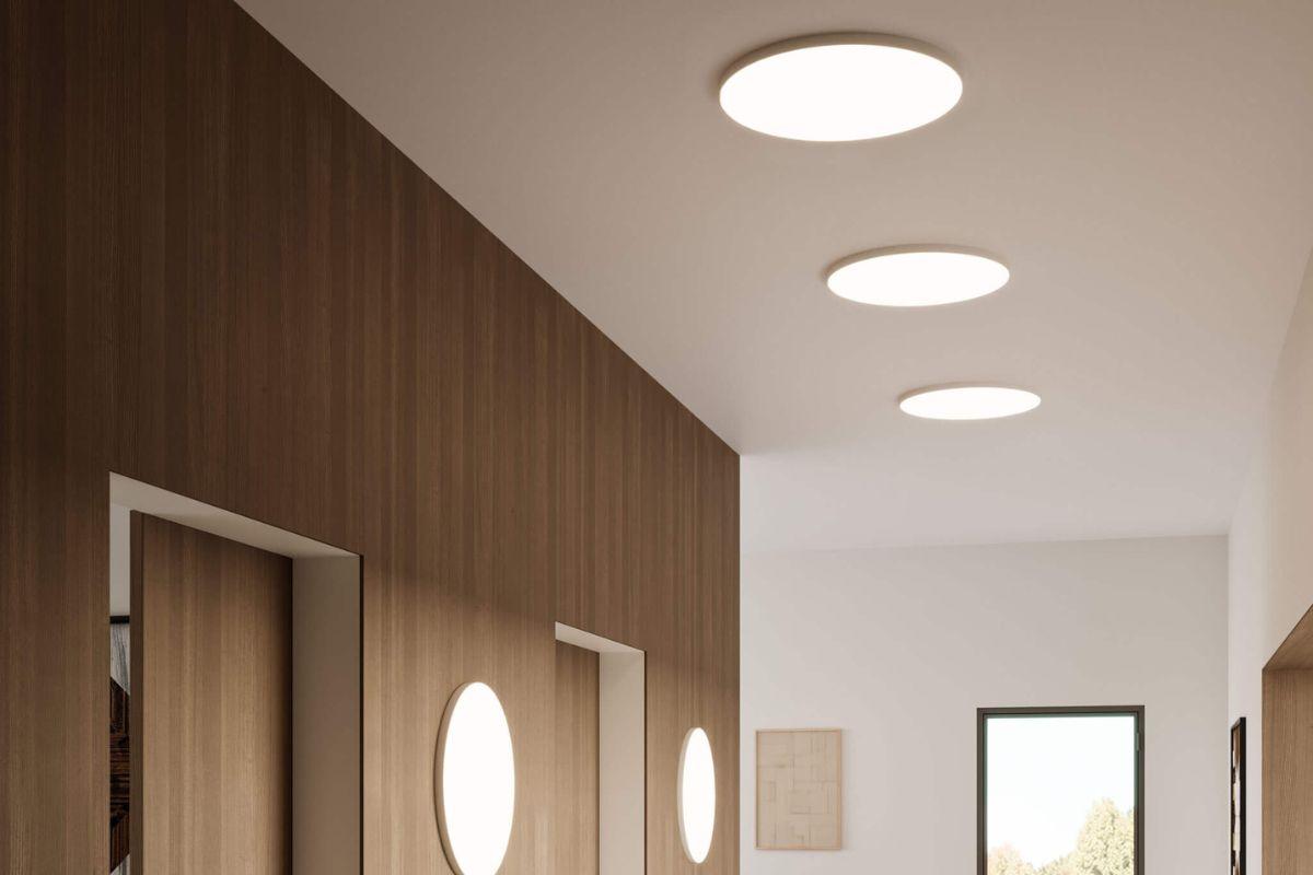 Round white flush mount ceiling lights illuminating a modern hallway with wood accent walls