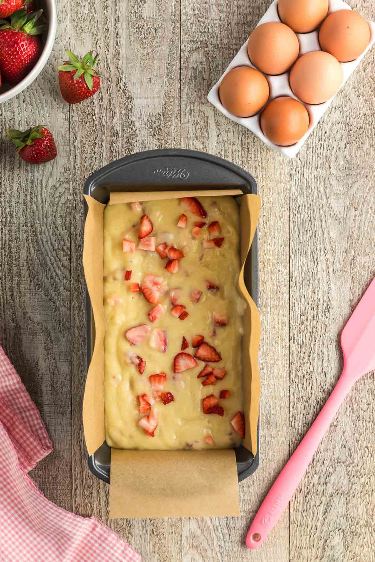 strawberry bread batter in loaf pan topped with strawberries