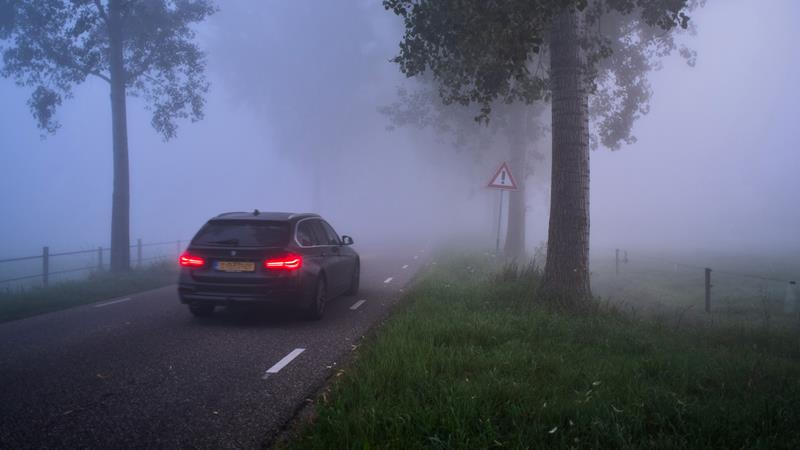 Vehicle with rear fog lights on driving through fog.