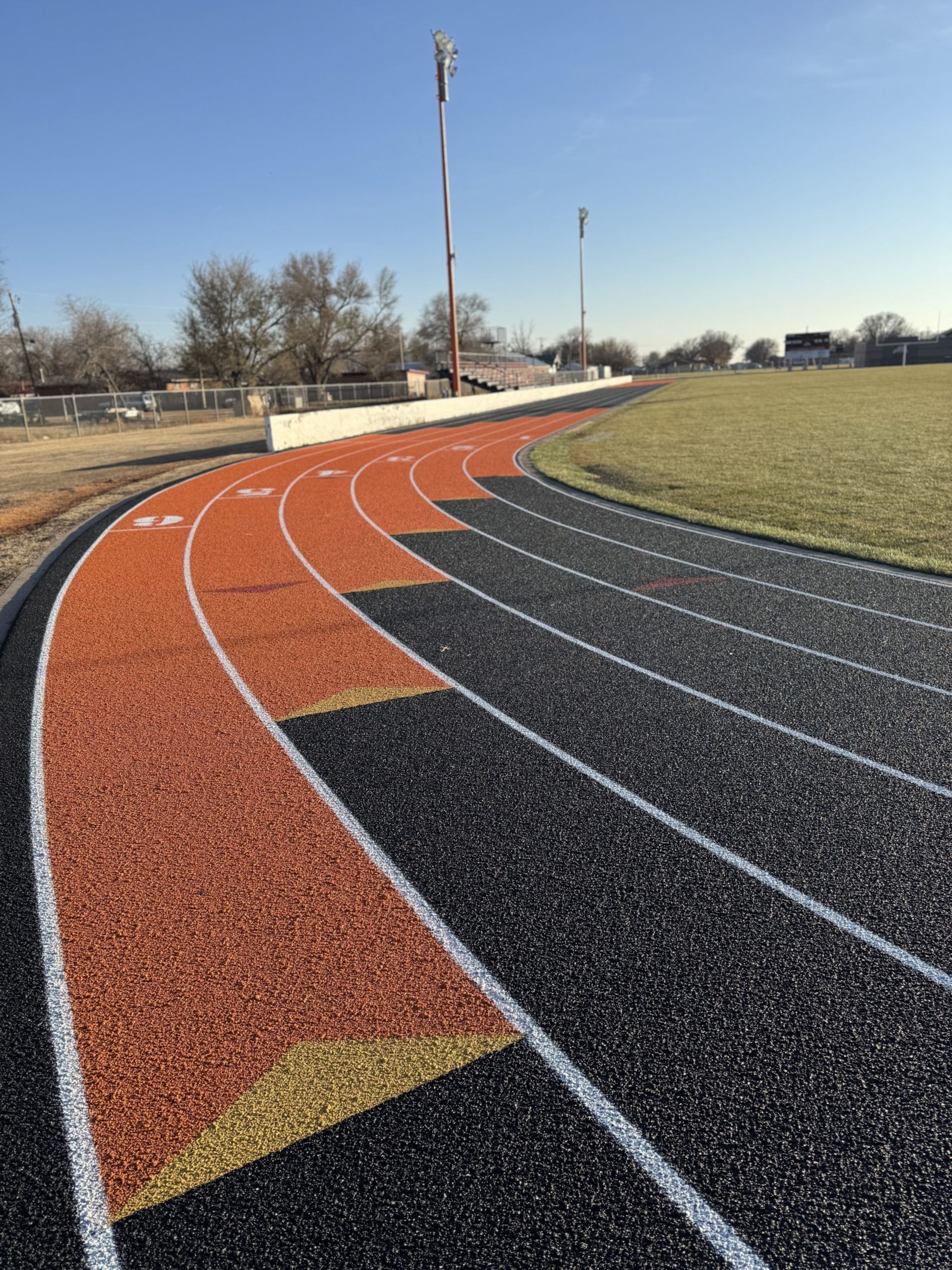 Resurfaced track at Ulysses High School in KS with a new, durable surface and vibrant orange structural spray in the exchange zones to improve performance and safety.