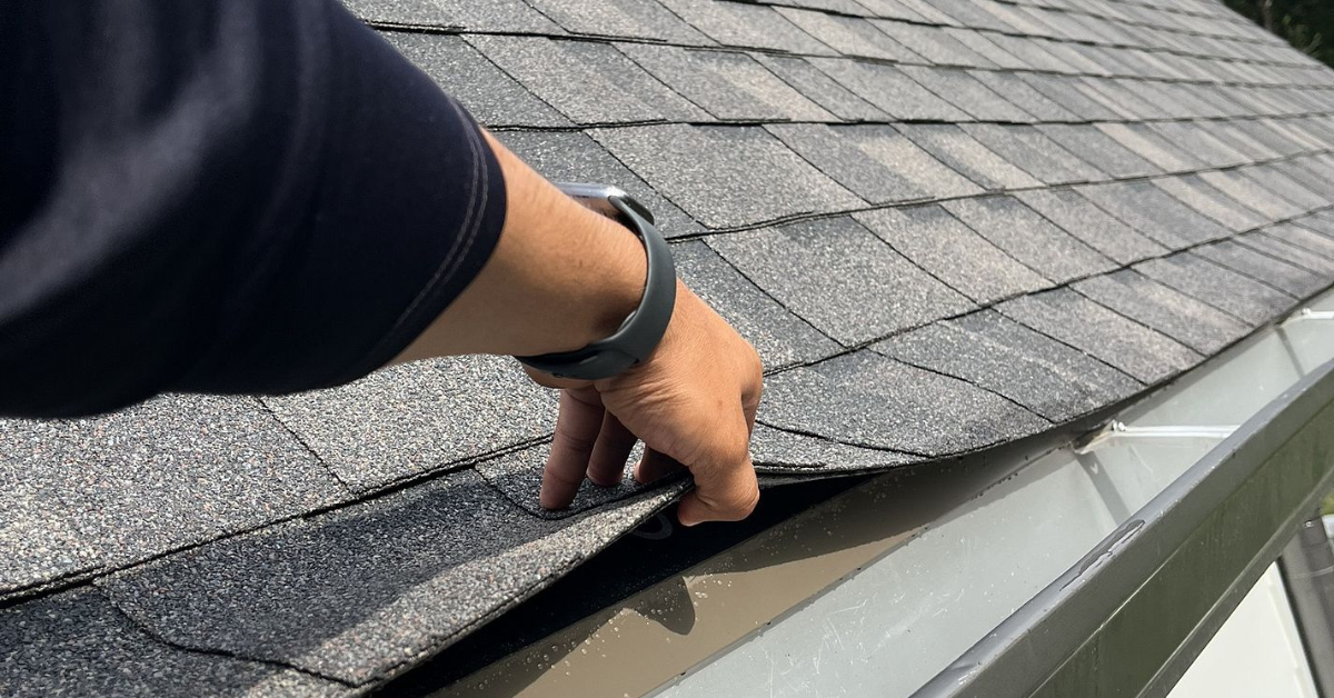 Professional roofer in safety gear working on a steep roof using Five Points Roofing branded underlayment during a roof replacement project in Middle Tennessee.