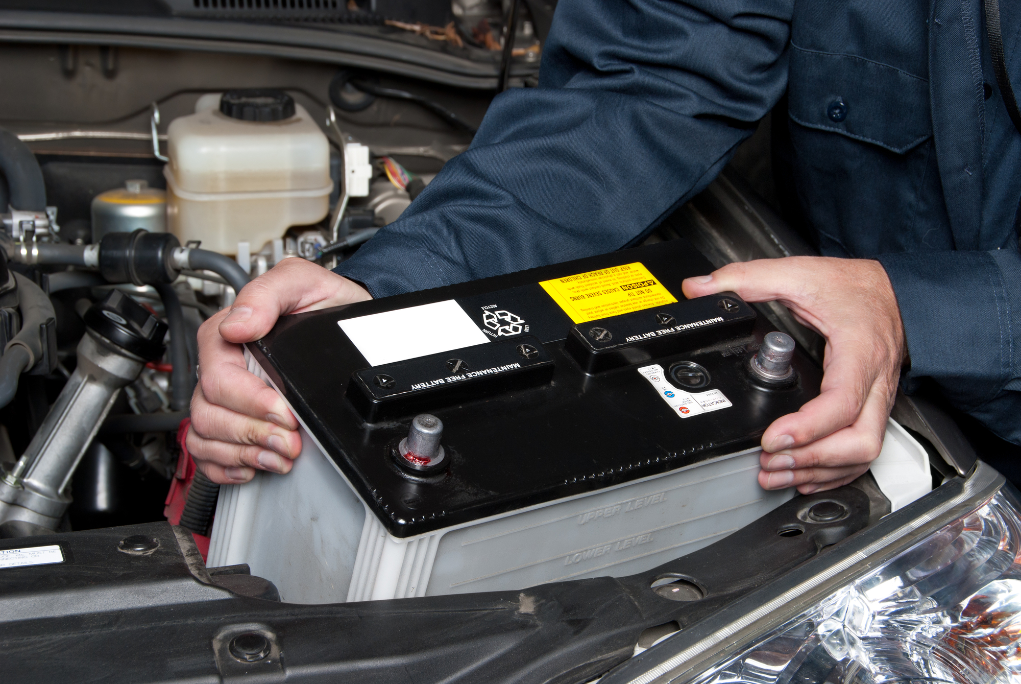 Car mechanic replacing vehicle's battery.