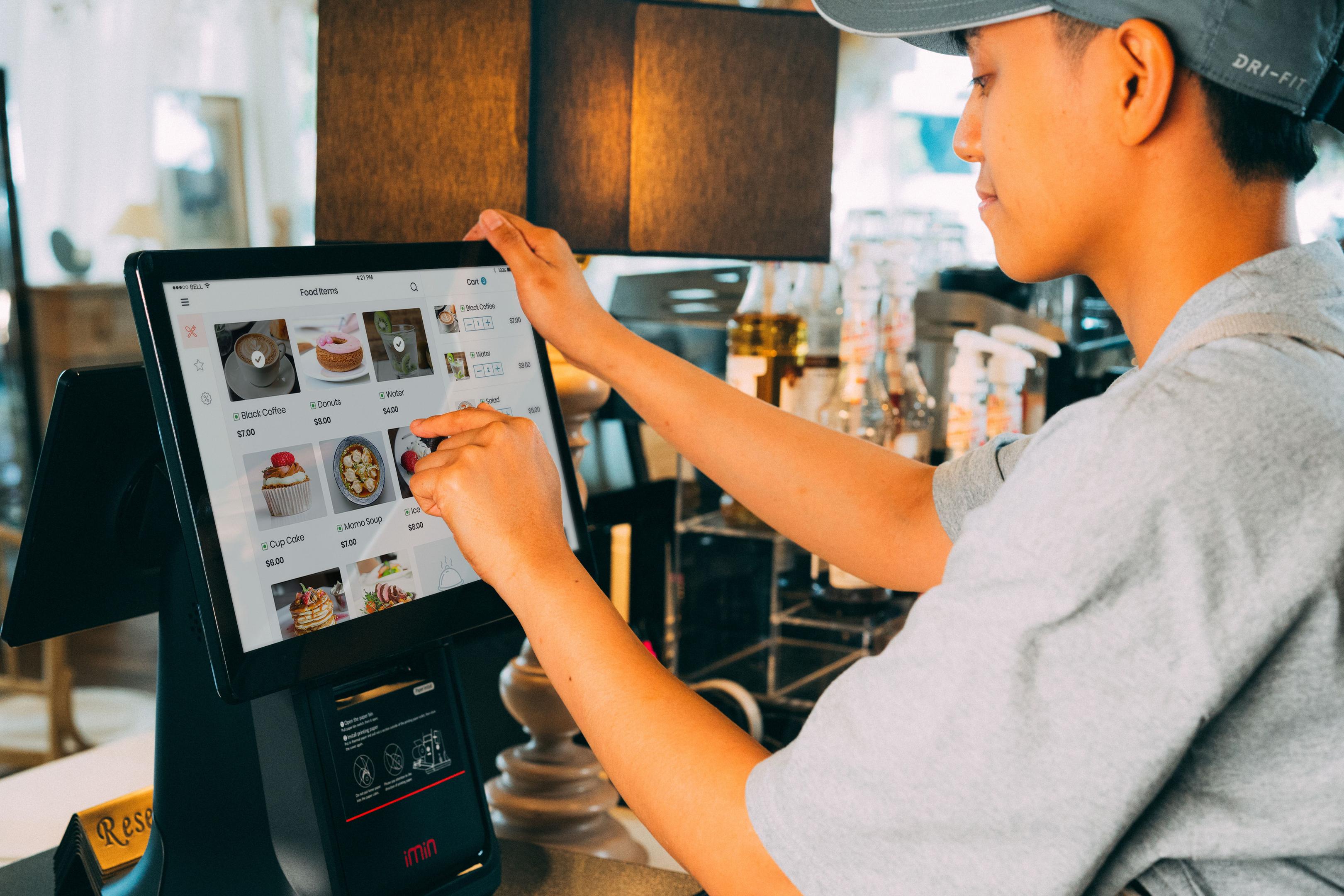 A person holding a smartphone to their ear while examining a restaurant takeout menu on a counter