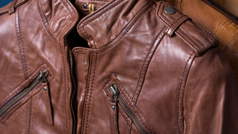 A close up image of a brown leather jacket on a hanger