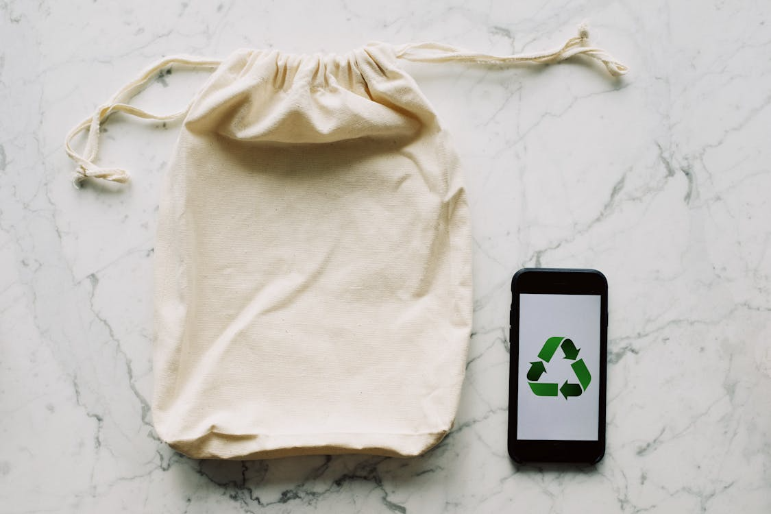 White textile bag and smartphone with recycle logo