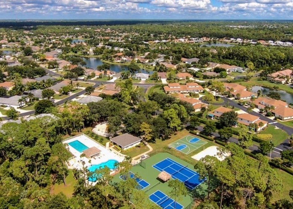 The image depicts a resort-style community pool area surrounded by lush palm trees and luxurious seating options, highlighting the inviting atmosphere of a desirable gated community in Naples, FL. This vibrant space features two heated swimming pools, perfect for outdoor living and relaxation.