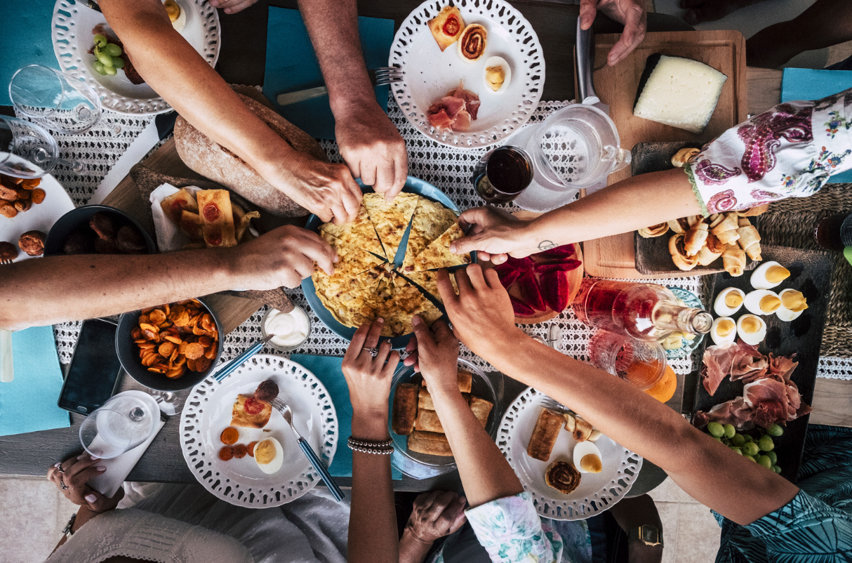 Group reaching for pitta bread slices on table
