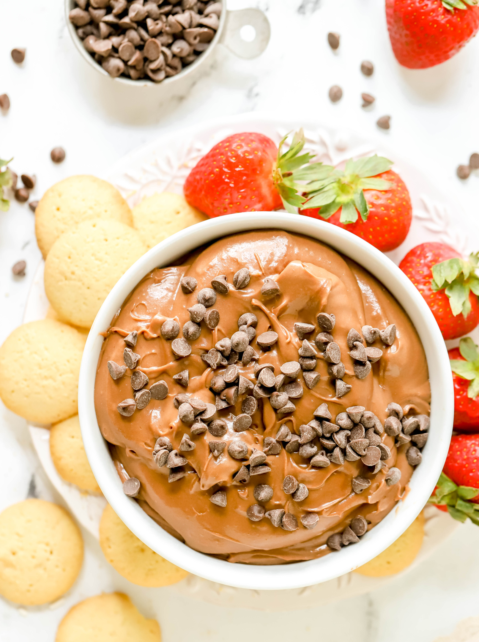 bowl of brownie batter dip on a plate surrounded by Nilla wafers and strawberries