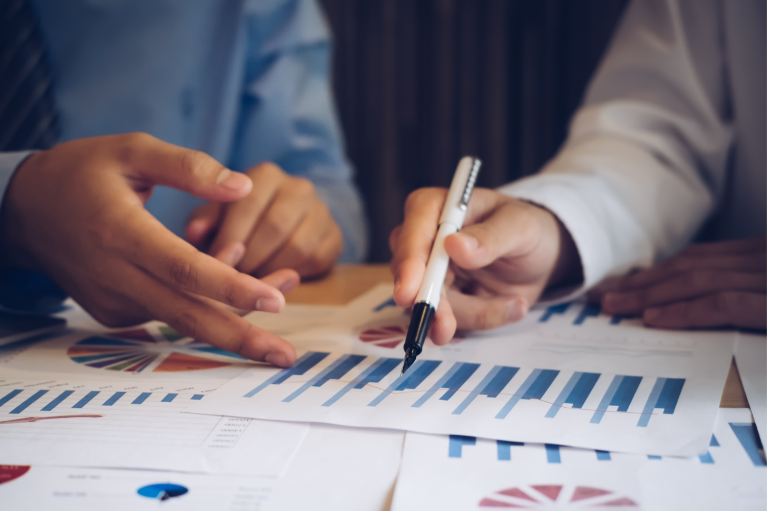 Two business people are looking at graphs on papers.