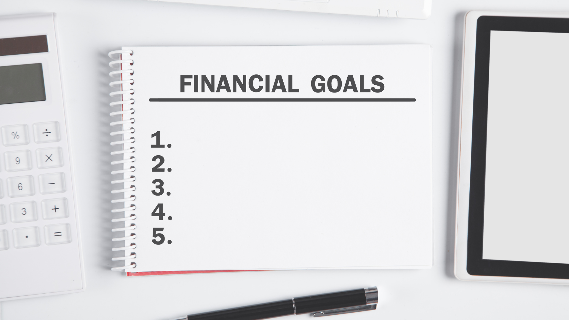notebook with financial goals on next to a calculator and electronic device