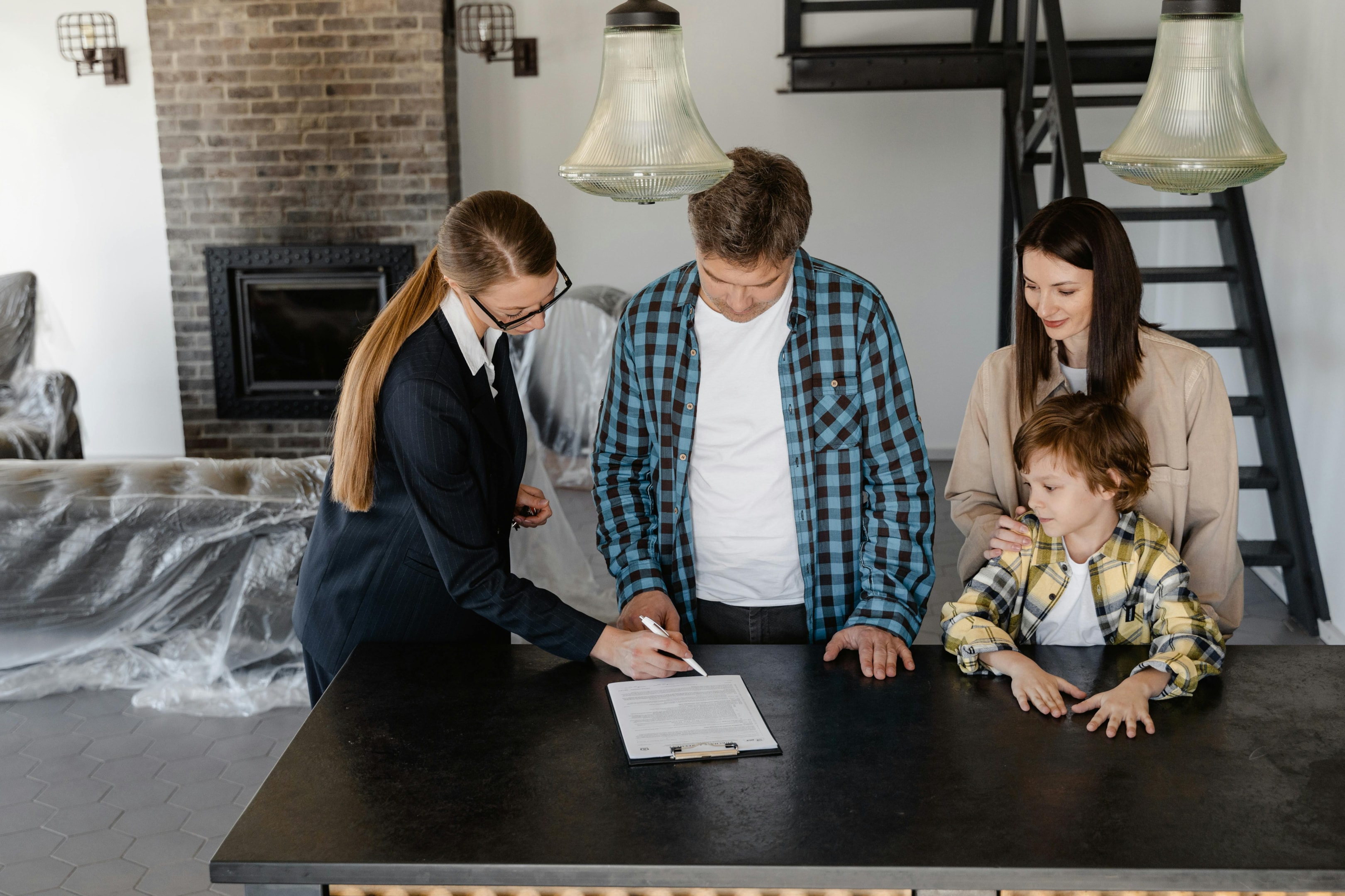 Real estate agent signing closing paperwork with homebuyers.