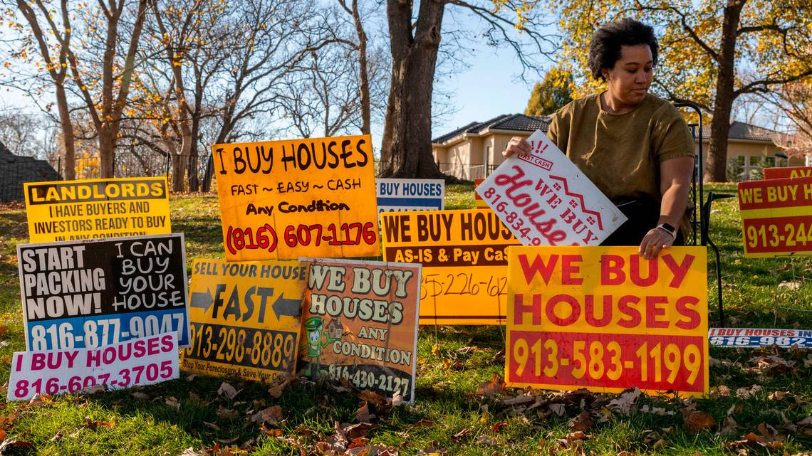 A house with a "We Buy Houses" sign in front of it