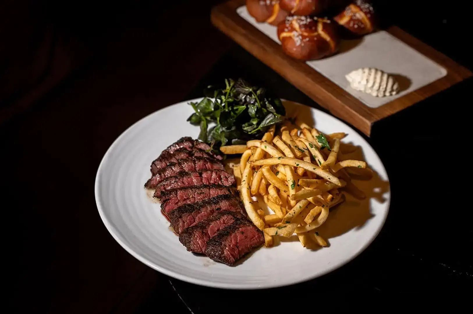 Singapore steakhouse sliced grilled steak with crispy fries and fresh greens on a white plate