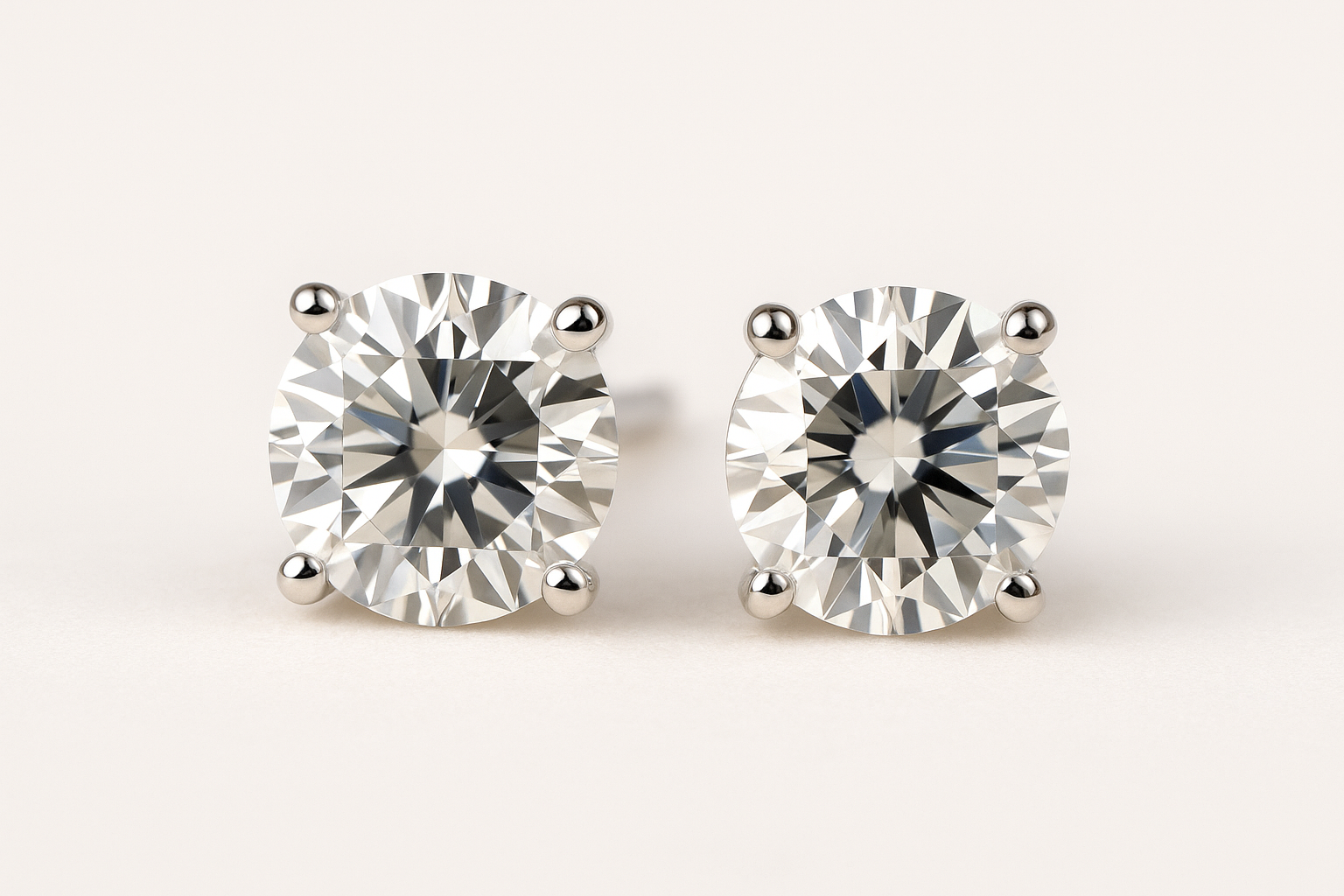 Klasikiniai auskarai vinukai su apvaliais brilianto šlifavimo deimantais, įstatytais į baltą auksą, ant šviesaus fono