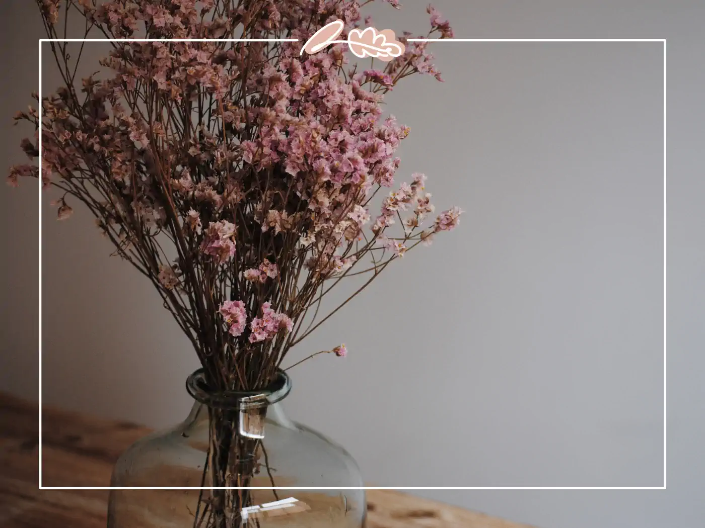 A tall glass vase filled with a bouquet of dried pink flowers, creating a charming rustic decor piece. Fabulous Flowers and Gifts.