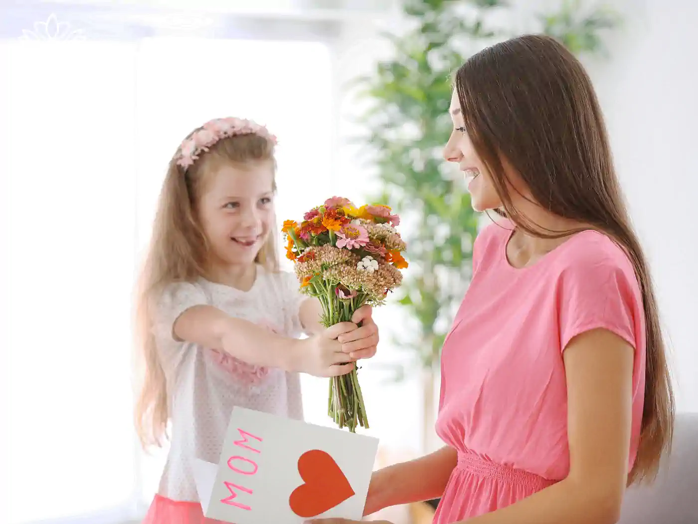 Image of a young girl giving a flower bouquet to her smiling mother, who is holding a card. Fabulous Flowers and Gifts - Luxury Flower Bouquets.