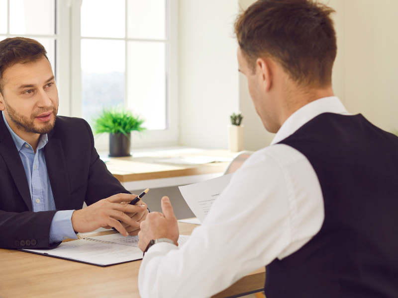 An image showing a person talking to a lawyer about an auto accident settlement claim after suffering bodily injury.