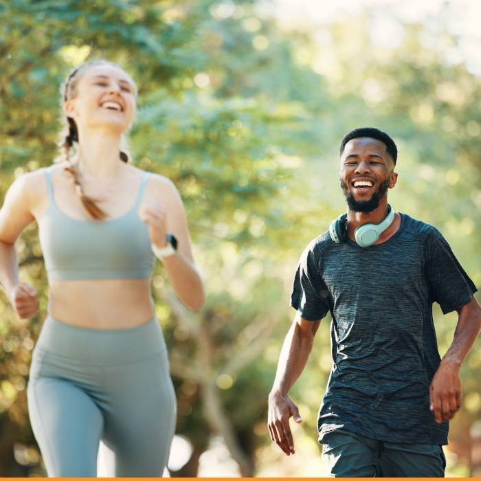 A vibrant image of a young man and woman jogging through a lush park, both smiling and enjoying their run. This captures the essence of wellness and a healthy lifestyle promoted by The Good Stuff Health Shop South Africa, part of the TERRA NOVA Collection, offering customers a range of health supplements, essential oils, homeopathic remedies, and vitamins to support their journey in life.