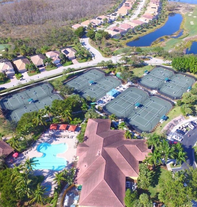 The image showcases community tennis courts and recreational facilities within the prestigious gated community of Colonial Country Club in Fort Myers, featuring well-maintained courts surrounded by lush greenery and nearby access to a community pool and clubhouse. This vibrant setting promotes an active SWFL lifestyle, perfect for residents looking to enjoy tennis and other community amenities.