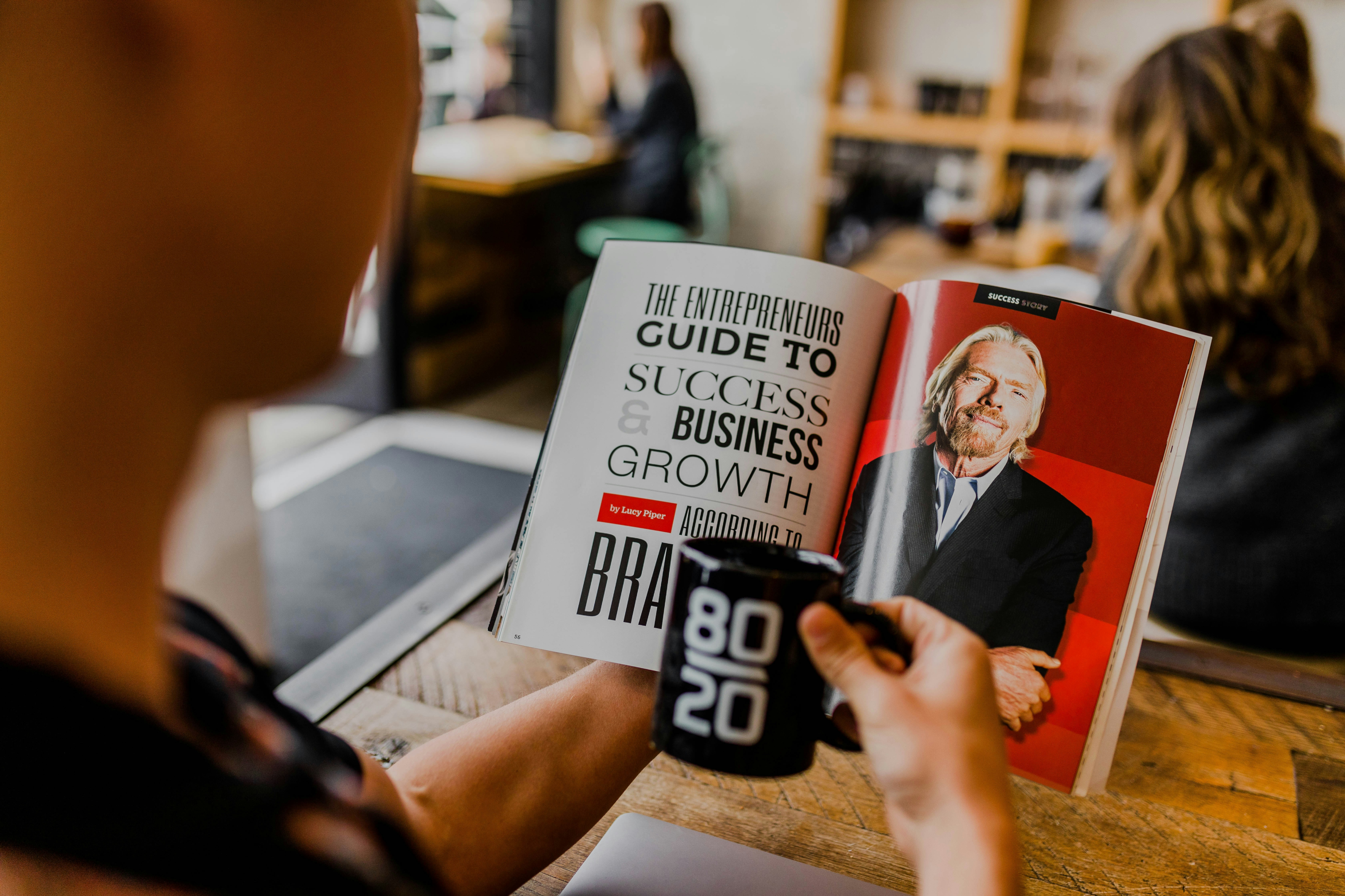Man holding a coffee mug with 80/20 written on it reading an entrepreneurs guide to success