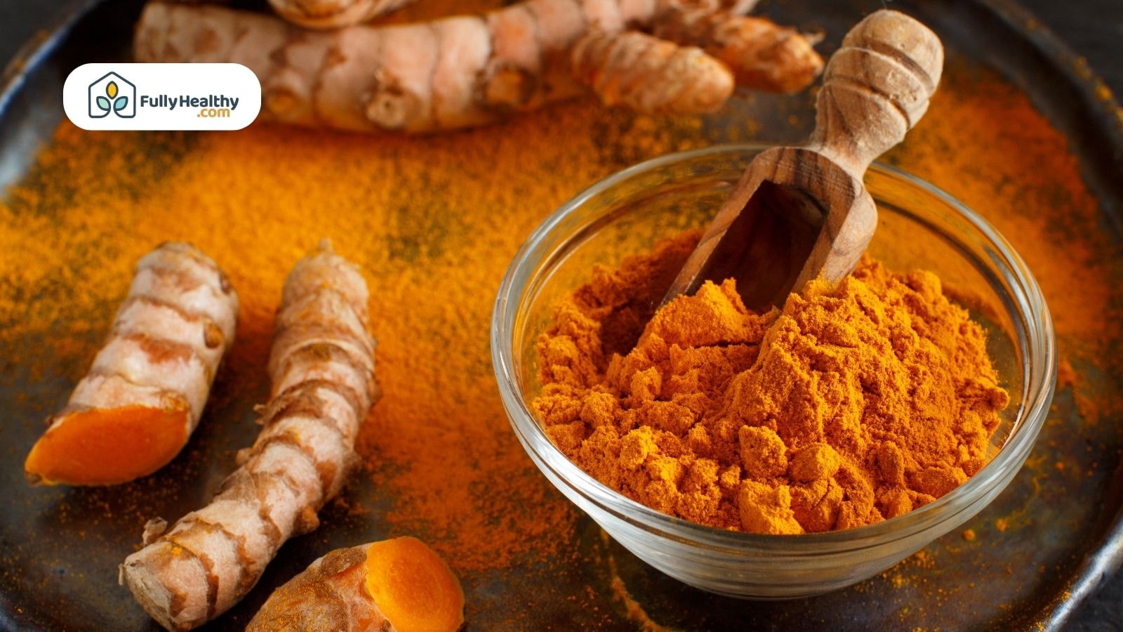 Bowl of turmeric powder with fresh turmeric root on a tray