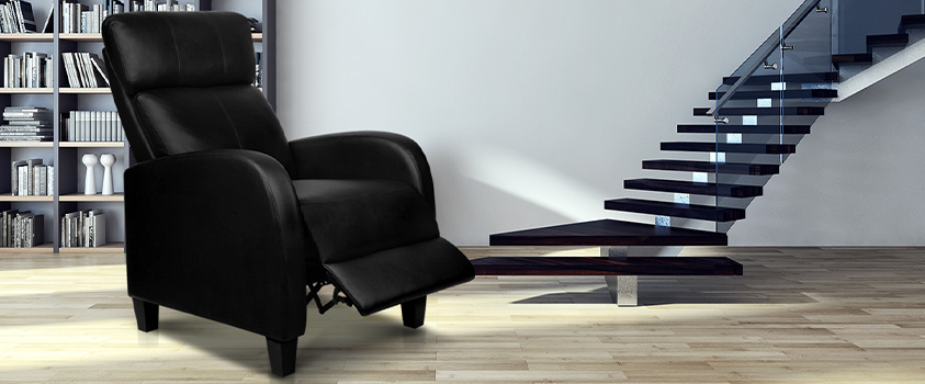 An Artiss Black PU Leather Reclining Armchair, set in a bright living room. In the background is a bookcase and a set of dark wood and glass stairs ascending.
