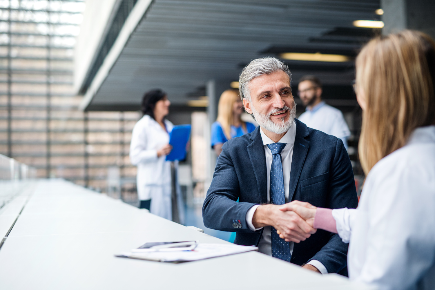 Two professionals in a business setting shaking hands.