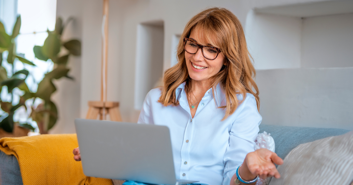 A cheerful woman on a cozy couch with a laptop; researching tax write-offs LLC.