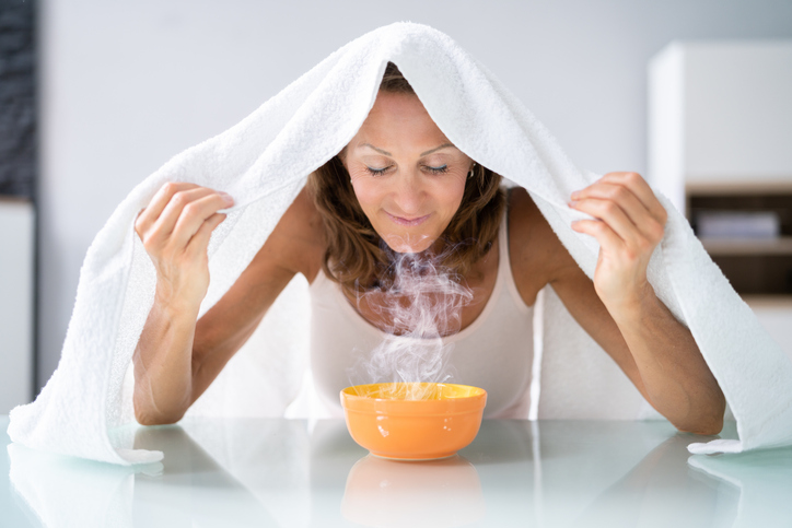 An image of a woman breathing steam for her allergies.