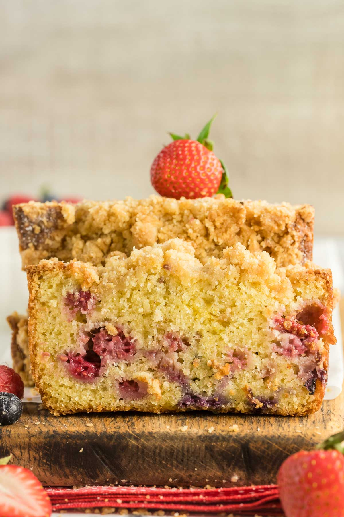slice of berry loaf cake leaning against a stack of slices