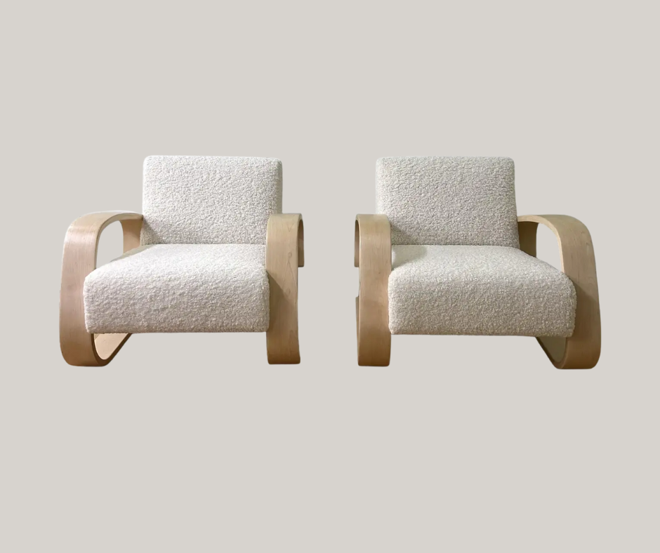 Two identical lounge chairs with light birch bent-wood arms and plush white boucle upholstery, positioned side by side.