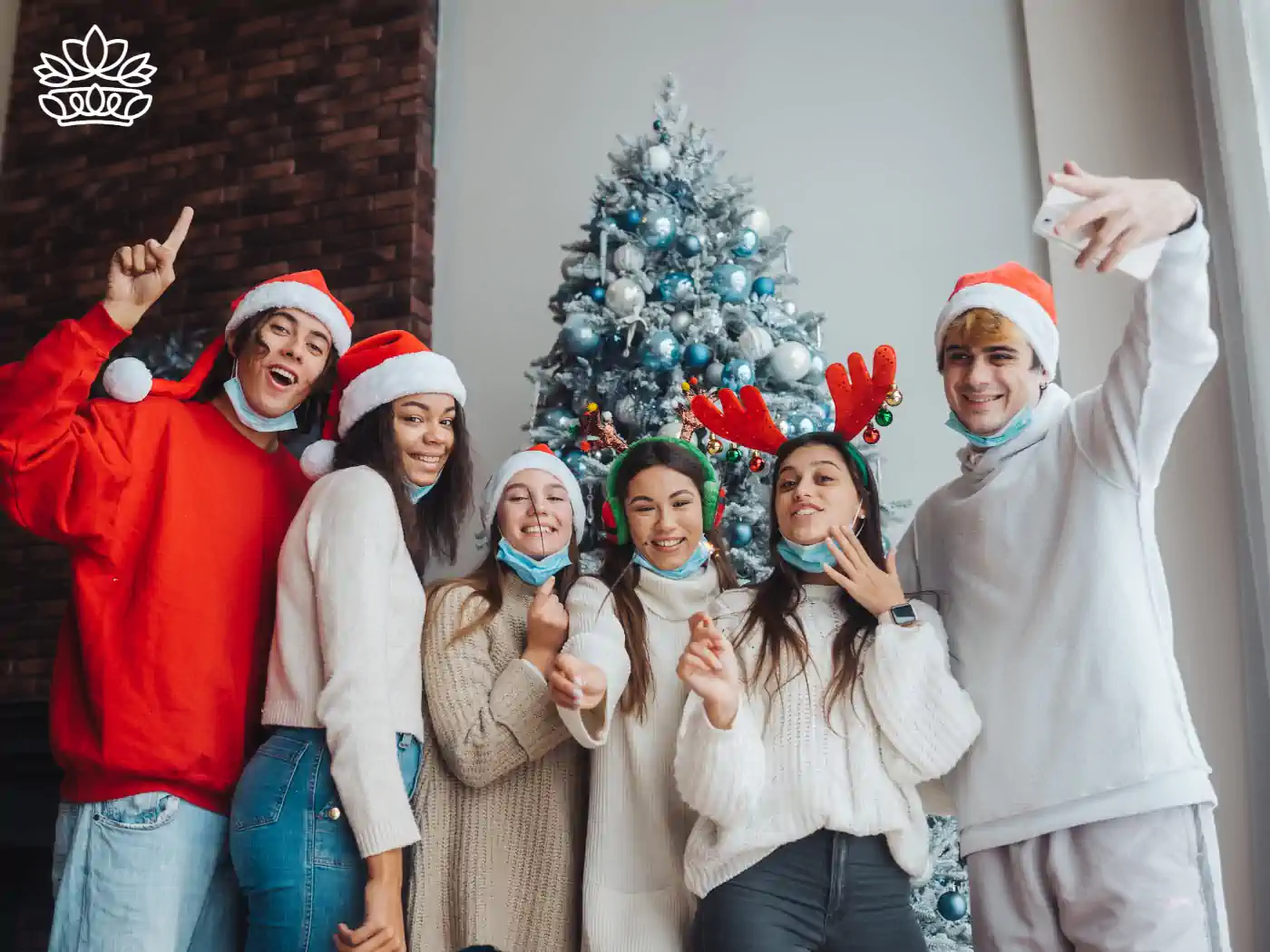 A group of friends celebrating the festive season with Santa hats and reindeer antlers, gathered around a beautifully decorated tree. Part of the Festive Season Flowers Collection. Delivered with Heart by Fabulous Flowers and Gifts.
