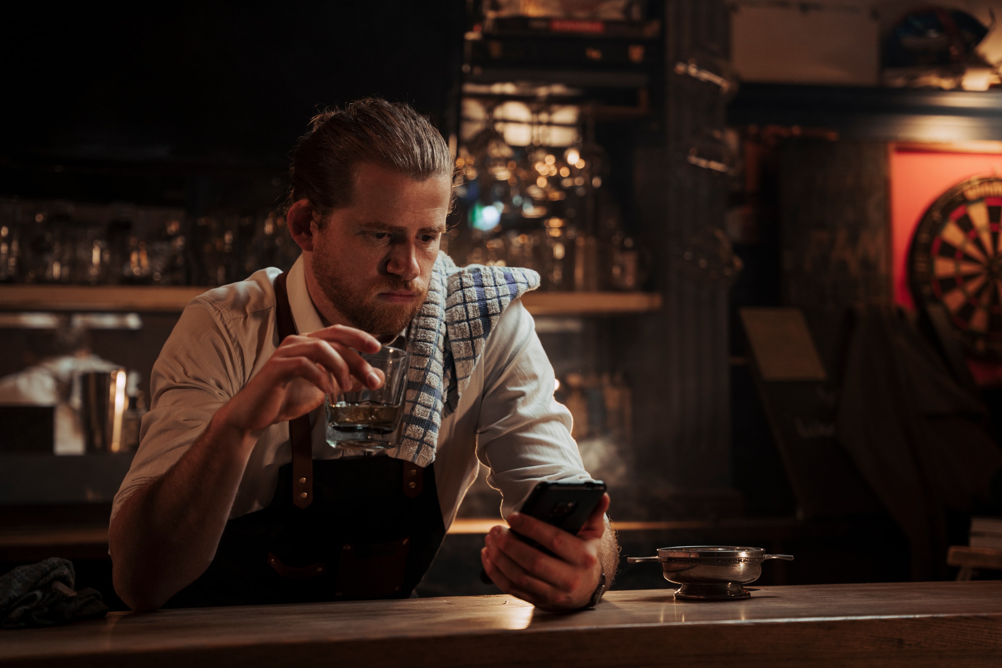 Bartender planning a mocktai menu with a drink in hand afterhours.