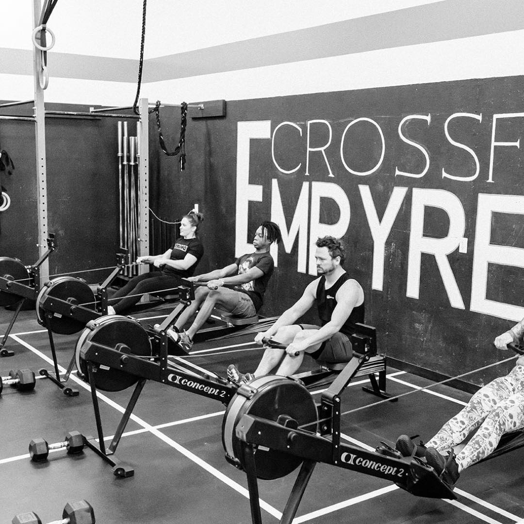 Group of people of different ages and skill levels doing CrossFit exercises in a gym, celebrating their success