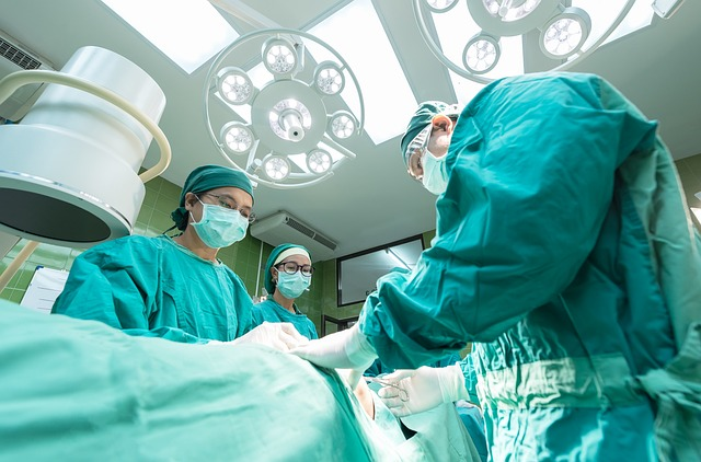 An image of a surgical team in green scrups operation on a patient.