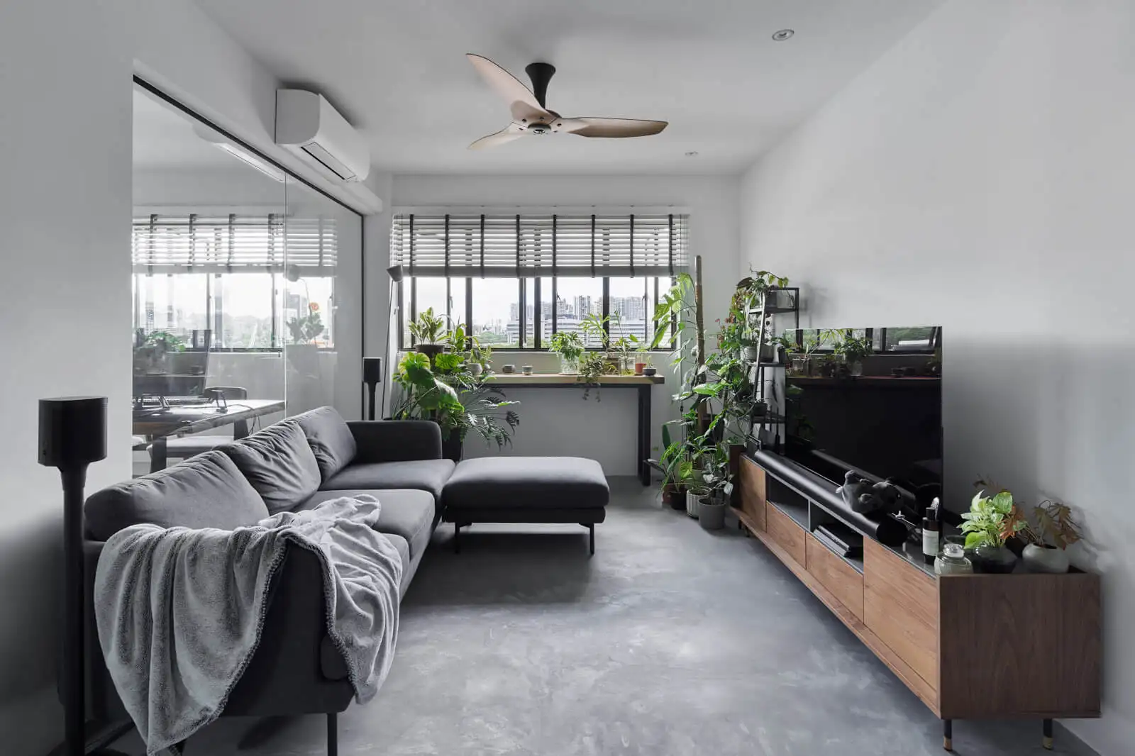 Industrial-style living room with lush plants and concrete floor showcasing sustainable condo interior design in Kuala Lumpur.