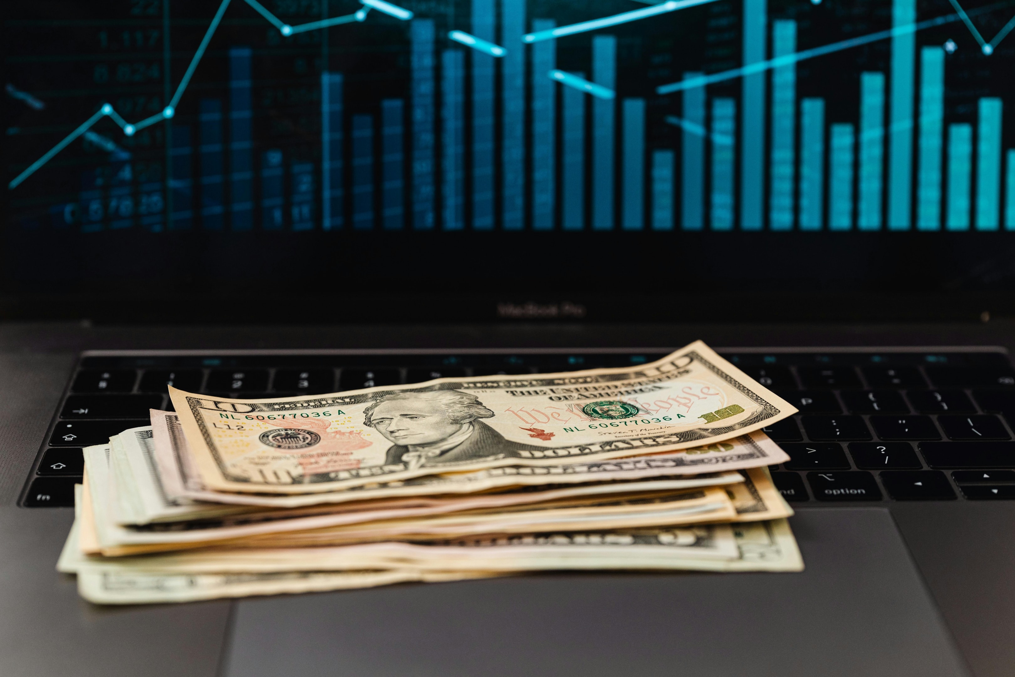 Stack of cash on open laptop of real estate investor as he tracks various KPIs associated with his probate lead outreach.